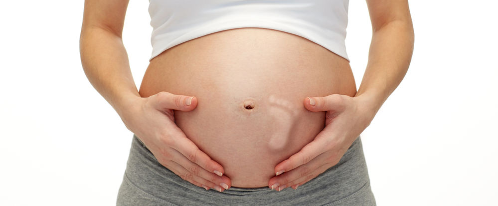 close up of pregnant woman touching her bare tummy