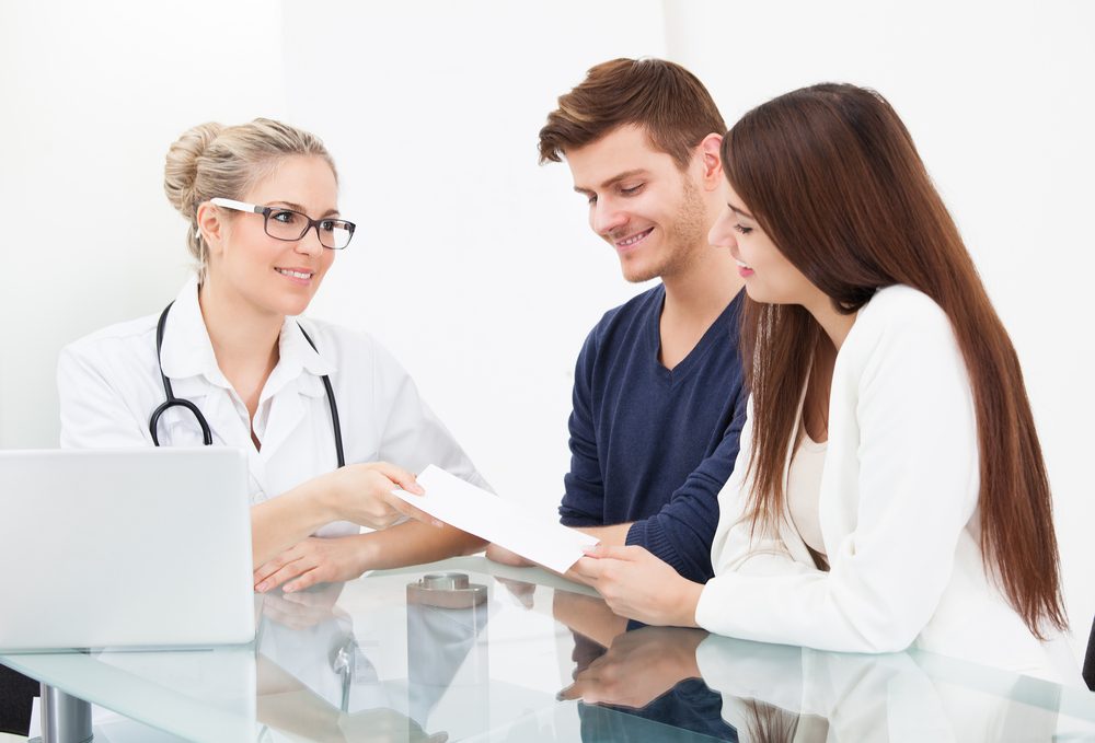 Doctor Giving Prescription Paper To Couple